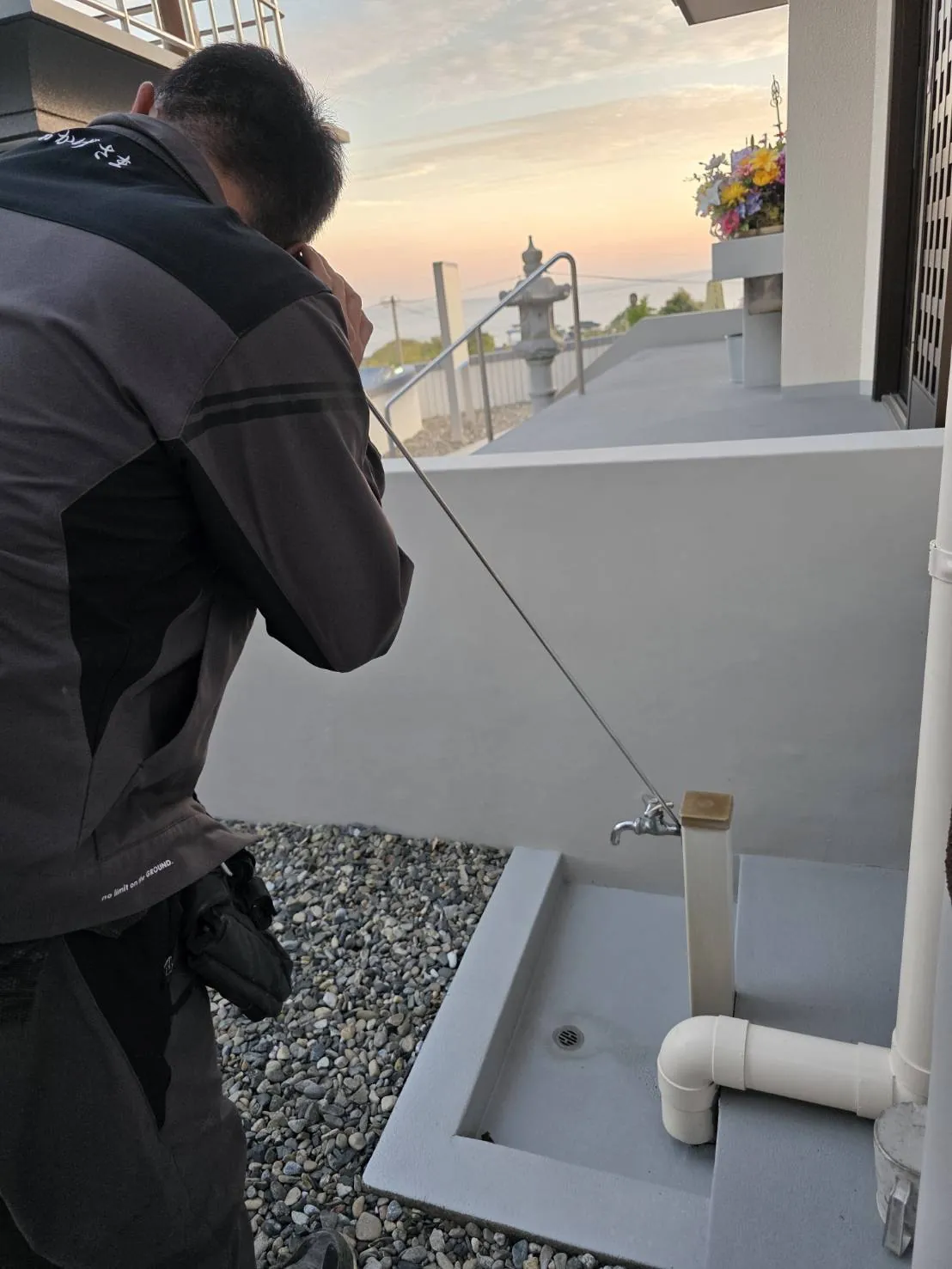 夕暮れの屋外で給水設備の点検を行う須納瀬設備工業所のスタッフ